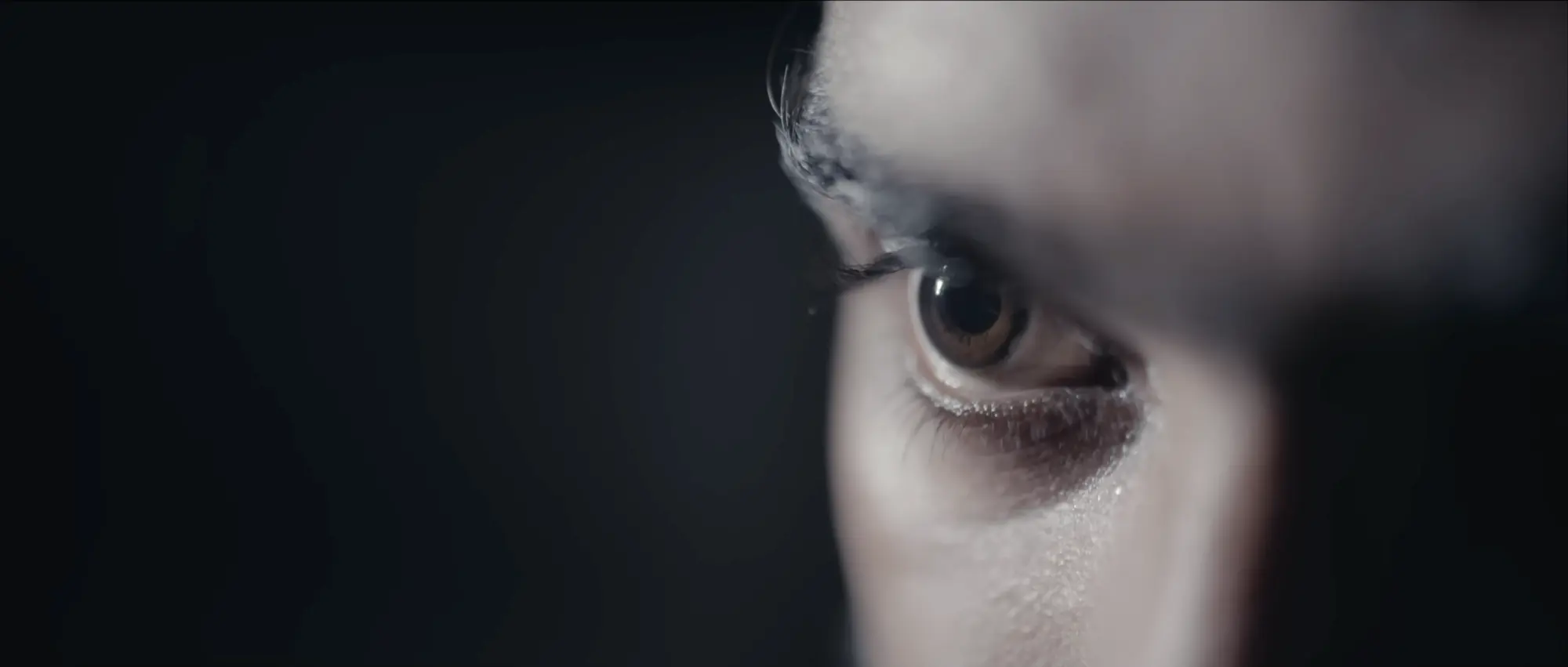 Close-up film still of an eye in low light