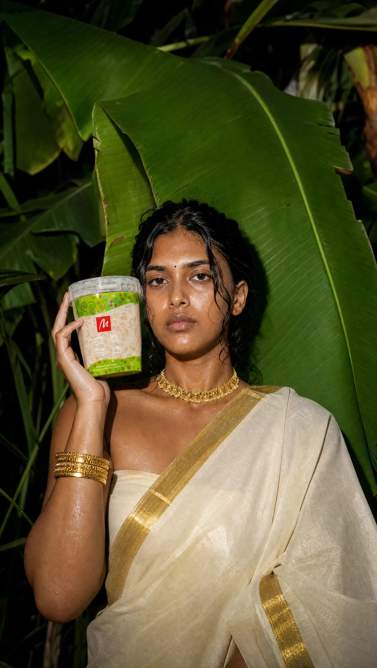 GenAI image: a woman in a Kerala kasavu saree holds a dessert tub against banana leaves